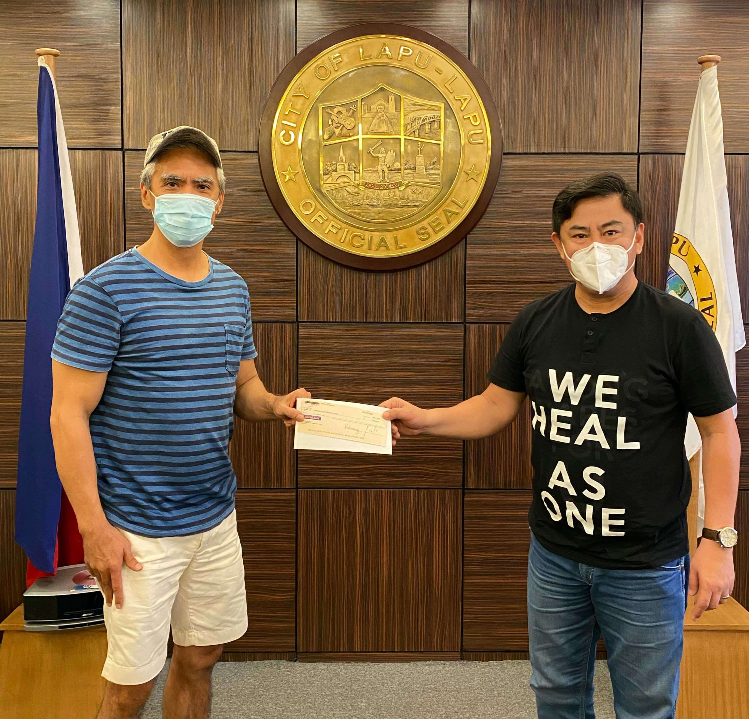 LAPU-LAPU CITY Mayor Junard “Ahong” Chan (right) receives a check for P2 million from businessman Michael Gleissner, represented by Joe Mercado (left), to aid in the city’s efforts to contain the Covid-19 virus.