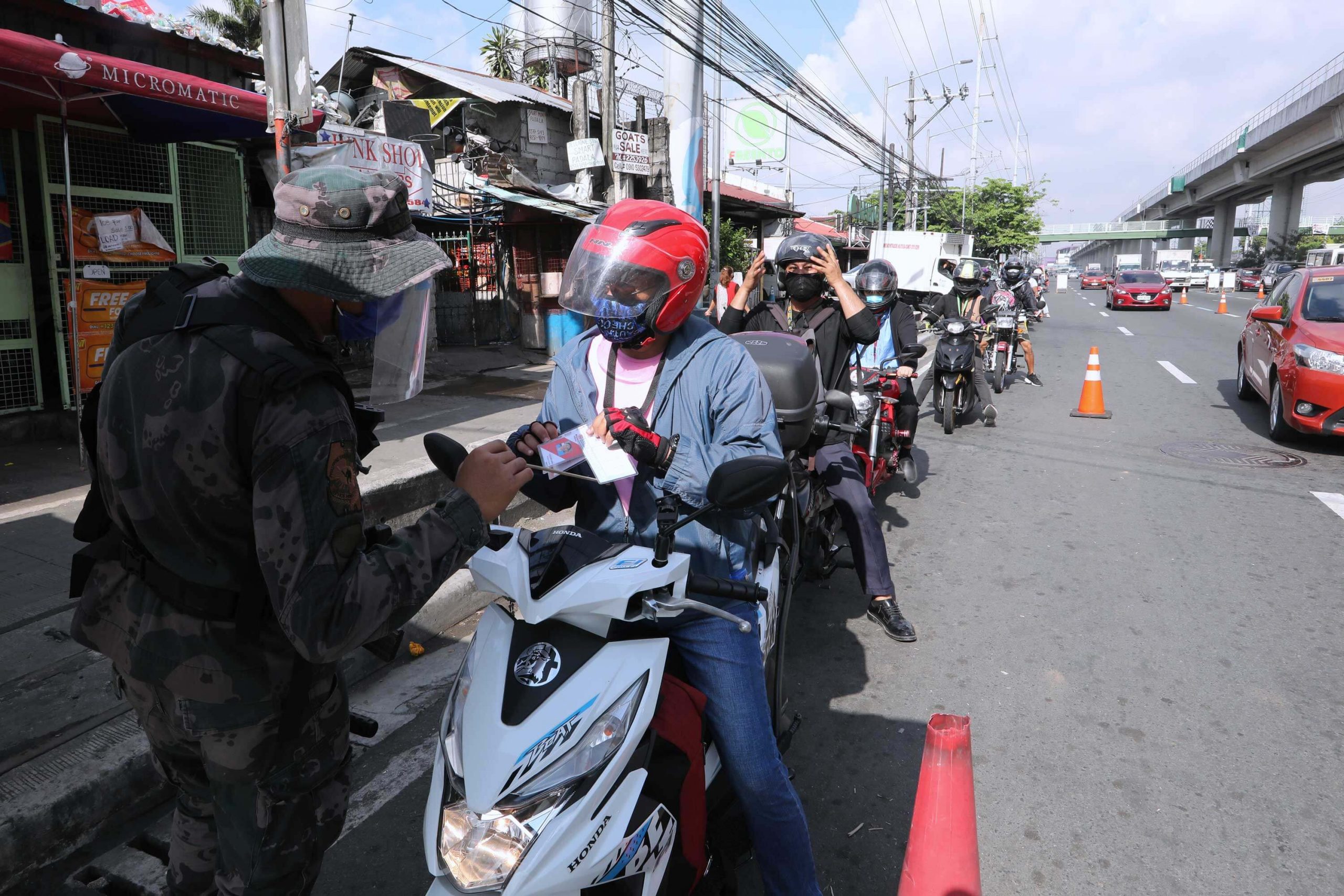 INSPECTION. A police officer inspects IDs and other documents presented by motorcycle riders entering Antipolo City, Rizal. Checkpoints remain despite easing of some restrictions under the general community quarantine which took effect in the province on May 16. (PNA photo by Joey O. Razon)