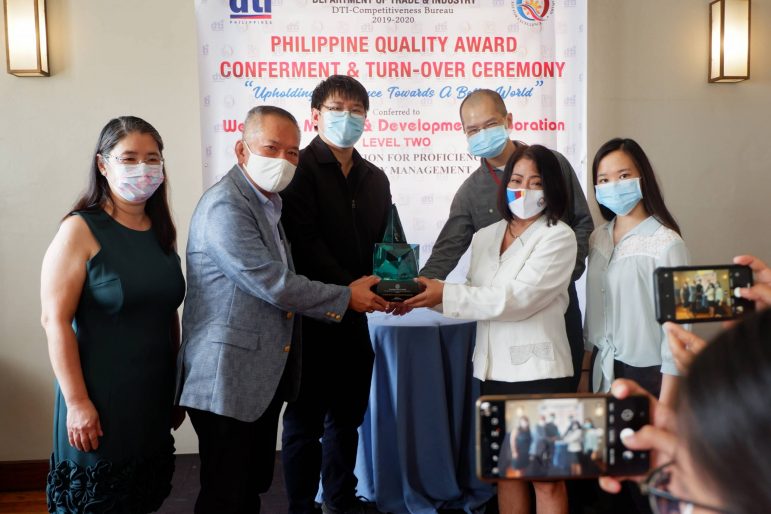 WORLD-CLASS QUALITY. Dr. Philip Tan receives from Department of Trade and Industry Competitiveness Bureau Director Lilian Salonga the trophy for Wellmade Motors and Development Corporation’s Philippine Quality Award (PQA) Level 2 recognition. With Tan are members of his family (from left) Judith Lee Tan, chief finance officer; Jefferson Phil Tan, vice president and chief operating officer; Jeffrey Philip Tan, vice president and chief administration and information officer; and daughter Phoebe Tan.
